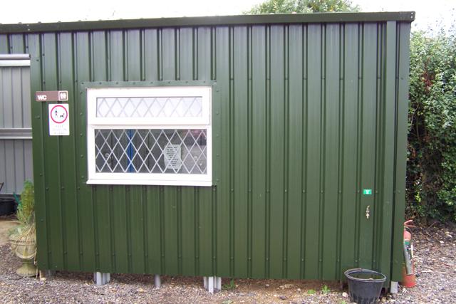 The side of a green building with a white window